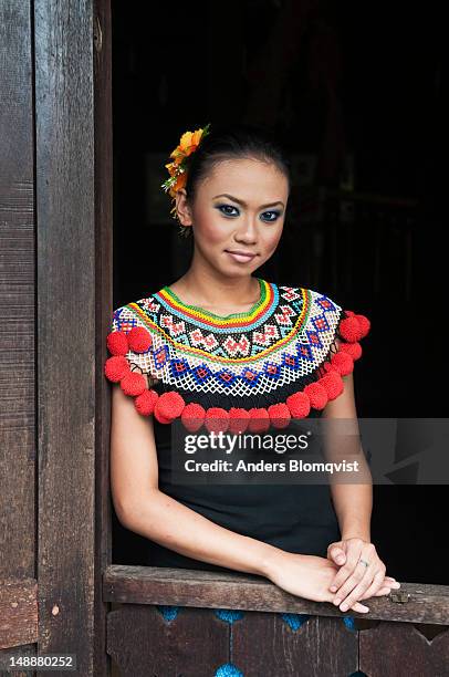 portrait of young iban tribal girl standing in longhouse window at sarawak cultural village near kuching. - iban stock pictures, royalty-free photos & images