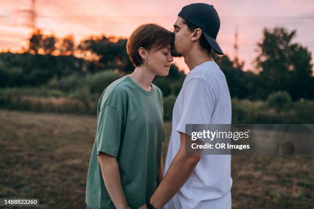 affectionate young couple in the countryside at sunset - forehead stock-fotos und bilder