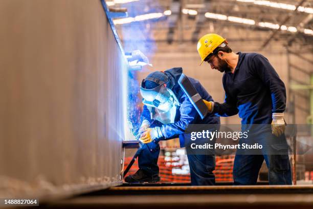 ingénieur enseignant à l’apprenti à utiliser une machine à souder - soudeur photos et images de collection