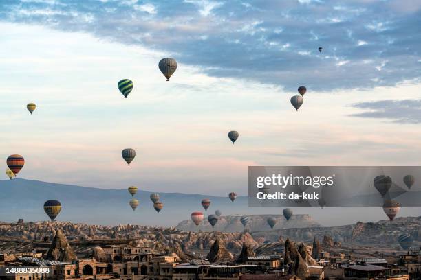hot air balloons flying over cappadocia valley at sunrise. moody morning lights and clouds - göreme stock pictures, royalty-free photos & images