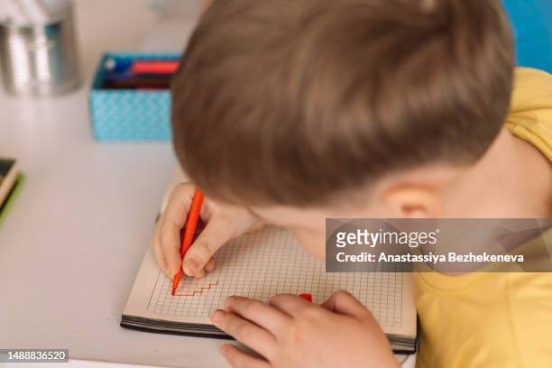 boy in yellow t-shirt draws in notebook, preschool education for children - letter t 個照片及圖片檔