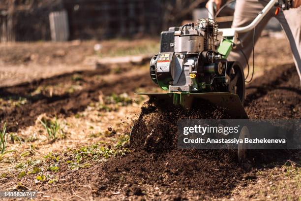 close up photo of gardener cultivate ground soil rototiller, prepare for planting crop - harrow agricultural equipment stock pictures, royalty-free photos & images