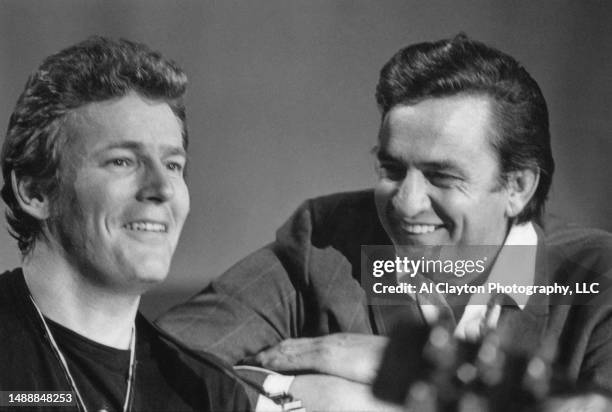 Musicians singer songwriters Gordon Lightfoot wearing a black tee shirt and Johnny Cash wearing a black suit with white shirt sitting shot close up...