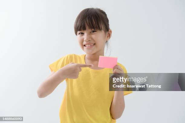 child pointing on empty pink sheet of paper, isolated on white background. portrait of a kid holding a blank placard, poster. mockup, copyspace. - small placard stock pictures, royalty-free photos & images