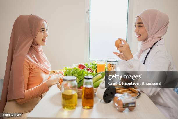 nutricionista musulmán asiático que trabaja aconseja una nutrición para el paciente que come un huevo todos los días. - hiyab fotografías e imágenes de stock