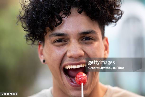 a young man opens his mouth to devour a delicious lollipop - biting lollipops stock pictures, royalty-free photos & images