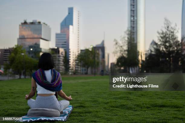 a serene woman sits poised as she meditates in front of a cityscape - santiago chile skyline stock pictures, royalty-free photos & images