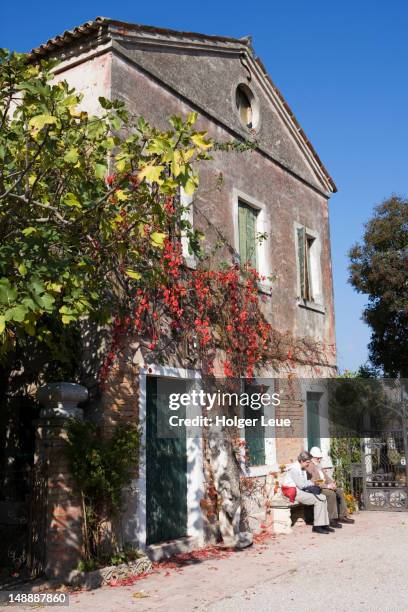 couple on bench by old building. - torcello stock pictures, royalty-free photos & images