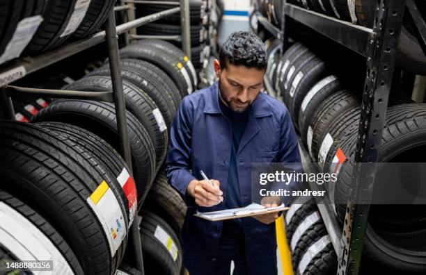 man doing a stock inventory while working at a tire factory - tyre shop stock pictures, royalty-free photos & images