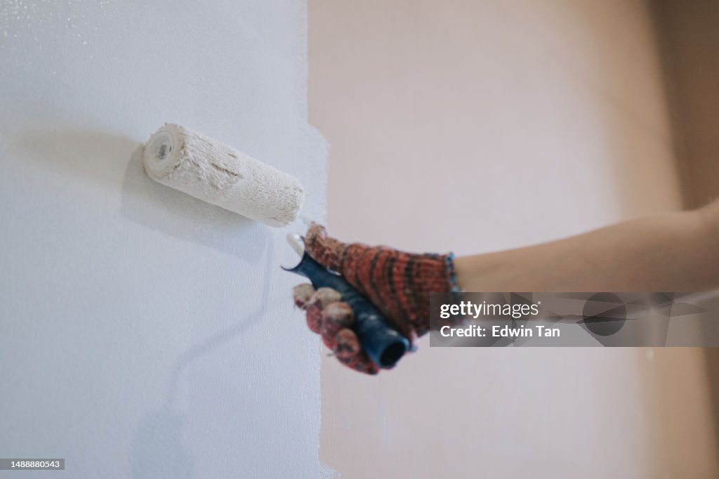 Mujer china madura asiática pintando habitación doméstica