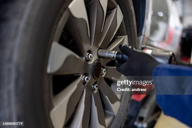 close-up on a mechanic fixing a flat tire on a car - alloy wheel stock pictures, royalty-free photos & images