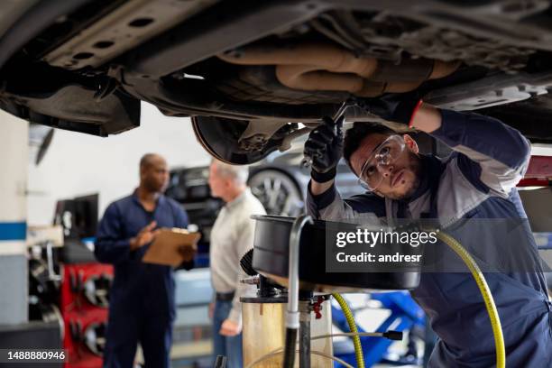 mechaniker arbeitet in einer autowerkstatt, die ein auto repariert - car jack stock-fotos und bilder