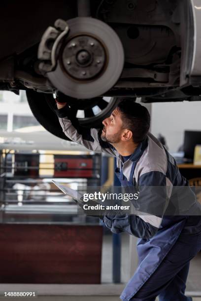 mecánico arreglando una llanta pinchada en un taller de reparación de automóviles - pieza de máquina fotografías e imágenes de stock