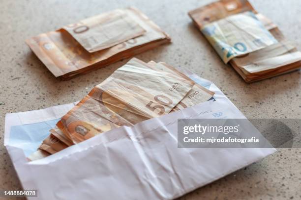 closeup of a hand holding a bunch of euro bills inside a white envelope - fajo de billetes de euro fotografías e imágenes de stock