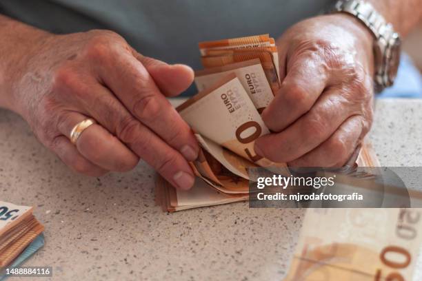 close-up of the hands of an adult man counting euro banknotes - fajo de billetes de euro fotografías e imágenes de stock