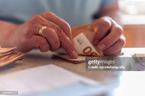 close-up of the hands of an adult man counting euro banknotes - fajo de billetes de euro fotografías e imágenes de stock