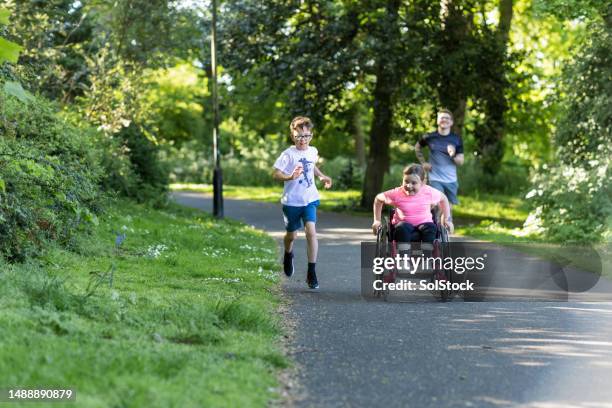 schnelles joggen im park - child in wheelchair stock-fotos und bilder