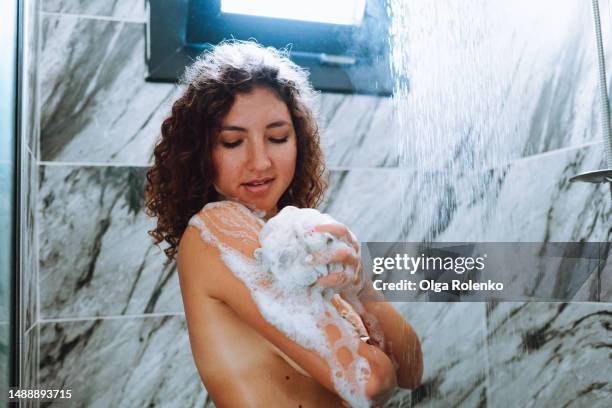 woman taking a shower with shower gel. curly naked woman under the streams of water - shower gel stock pictures, royalty-free photos & images
