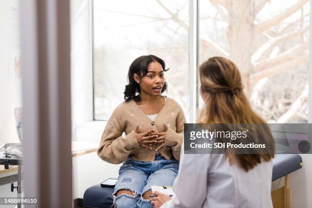 young adult female patient gestures while explaining her mental health struggles with the doctor - foundation conversations story of a girl stockfoto's en -beelden
