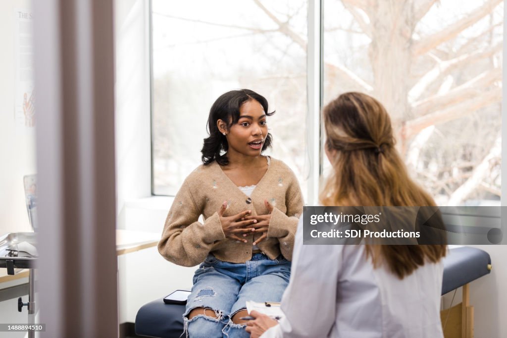 Young adult female patient gestures while explaining her mental health struggles with the doctor