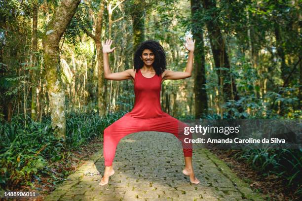 retrato de una mujer brasileña negra, vestida con un mono rojo, en pose de yoga al aire libre - dios fotografías e imágenes de stock