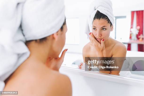 face care routine, applying nourishing lotion and cream, female in towel taking time to admire face skin pampering in the mirror. waist up - tonic water stock pictures, royalty-free photos & images