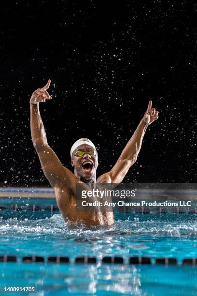 male black swimmer raises his arms after winning a race. - sports competition format stock pictures, royalty-free photos & images