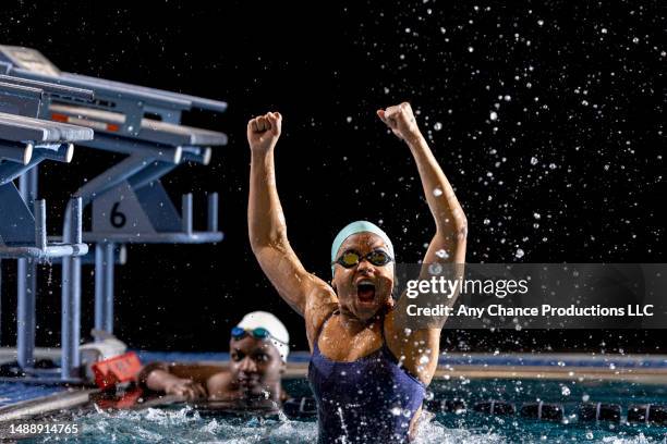 female swimmer celebrates winning a race. - championship stock pictures, royalty-free photos & images