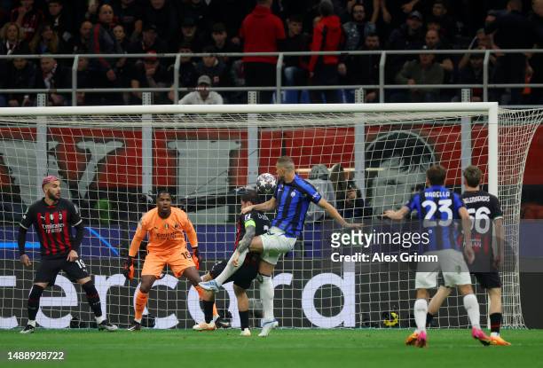Edin Dzeko of FC Internazionale scores the team's first goal whilst under pressure as Mike Maignan of AC Milan looks on during the UEFA Champions...