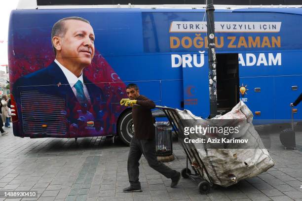 An elderly garbage collector walk past near the poster of Turkish President and People's Alliance's presidential candidate Recep Tayyip Erdogan on...
