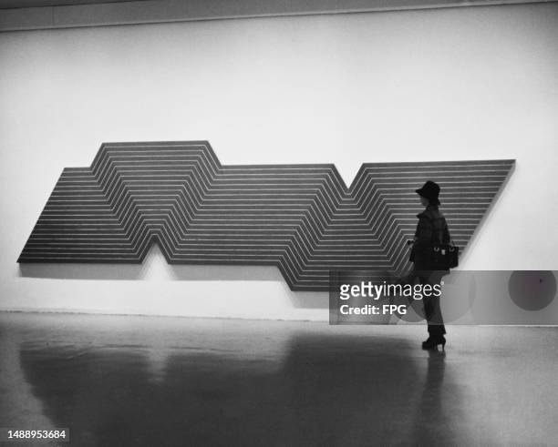 Woman looks at a painting by the American artist Frank Stella titled 'De la nada vida a la nada muerte' on display at the Museum of Modern Art, New...