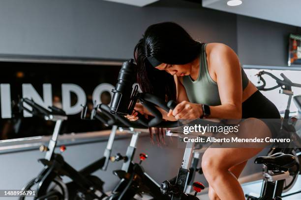 girls in the gym exercising on elliptical bike - spinning stock pictures, royalty-free photos & images