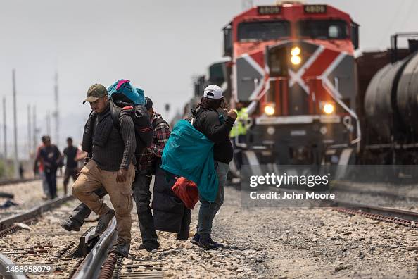 Migrant Train Riders Immigrants walk after disembarking from a freight train en route to ...