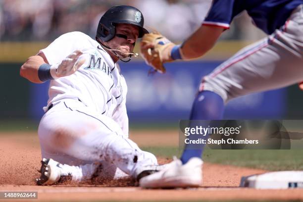 Jarred Kelenic of the Seattle Mariners slides safely into third base after his RBI triple during the eighth inning against the Texas Rangers at...