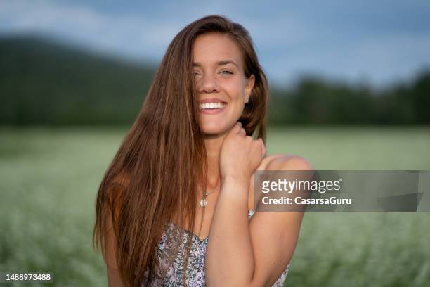 hermoso retrato de mujer sonriente feliz en un campo de hierba floreciente - largo florida fotografías e imágenes de stock