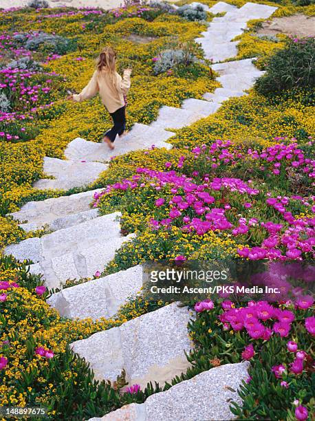 girl running down stone steps among flowers. - sardinien stock-fotos und bilder