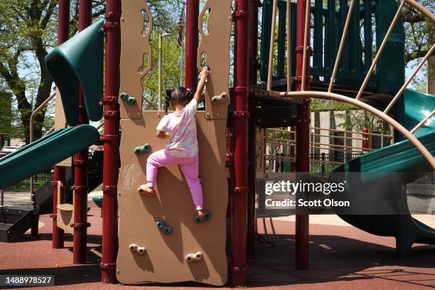 Five-year-old migrant girl from Venezuela plays on a equipment in the playground at Brands Park on May 10, 2023 in Chicago, Illinois. The field house...