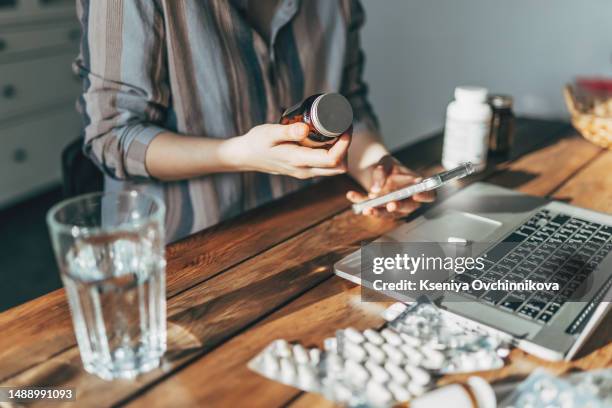 mature woman with blister pack of pills and smartphone in hand using online pharmacy store, buying pharmacy on internet, ordering medicine online at home. - drugs stock pictures, royalty-free photos & images