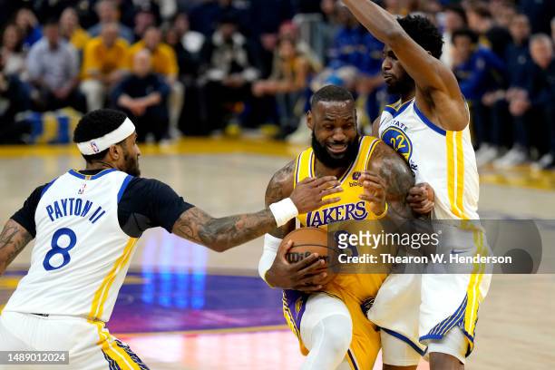 LeBron James of the Los Angeles Lakers drives to the basket against Gary Payton II and Andrew Wiggins of the Golden State Warriors during the first...