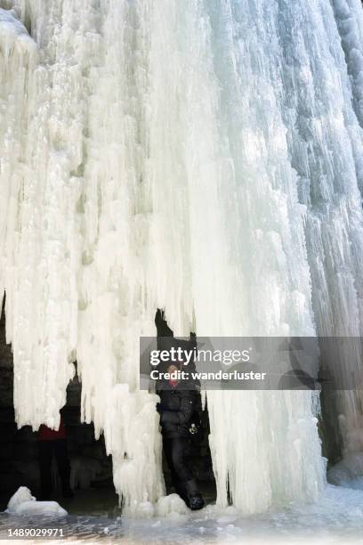 solo hiker under a frozen waterfall at maligne ice canyon, jasper national park - icefall stock pictures, royalty-free photos & images