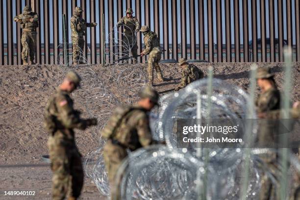 Texas National Guard soldiers uncoil concertina wire around a makeshift immigrant camp located between the Rio Grande and the U.S.-Mexico border...