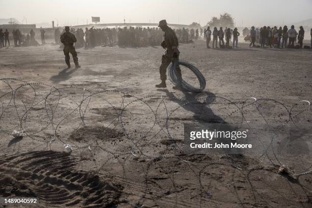 Texas National Guard soldiers place razor wire during a dust storm at a makeshift immigrant camp located between the Rio Grande and the U.S.-Mexico...
