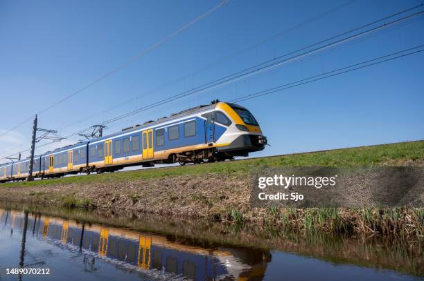 train of the nederlandse spoorwegen (ns) driving through a rural landscape during springtime - kampen overijssel stock pictures, royalty-free photos & images