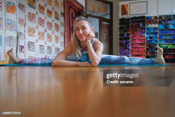 woman sitting in horizontal split and bending forward leaning on elbows, smiling at camera - upright position stock pictures, royalty-free photos & images