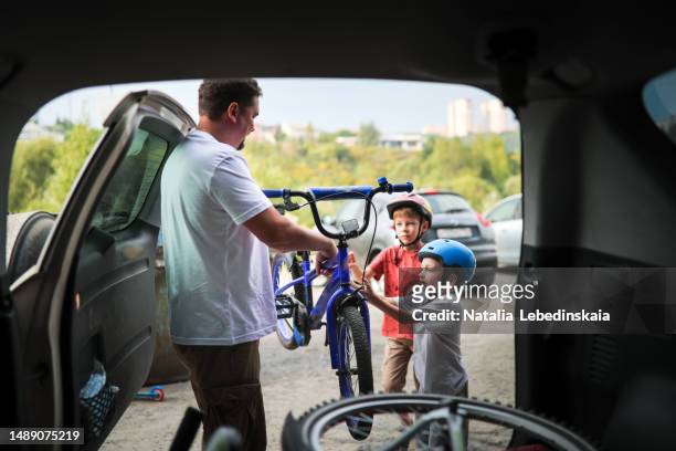 father and kids take out bicycles from trunk of car for walk in park. - kazakhstan man stock pictures, royalty-free photos & images