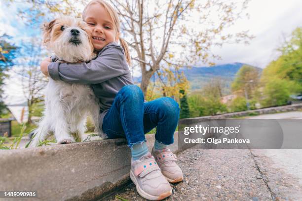 cute preschool girl hugs her dog sitting in yard - kind people stock pictures, royalty-free photos & images