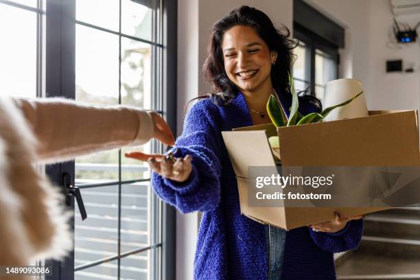 happy young woman receiving house keys to her new home from a landlord or previous owner - landlord stock pictures, royalty-free photos & images
