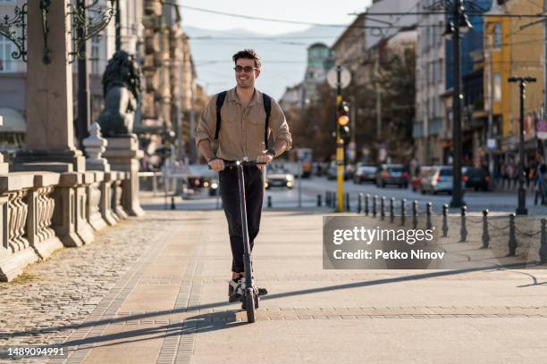 man riding e-scooter through city center - sofia stock pictures, royalty-free photos & images