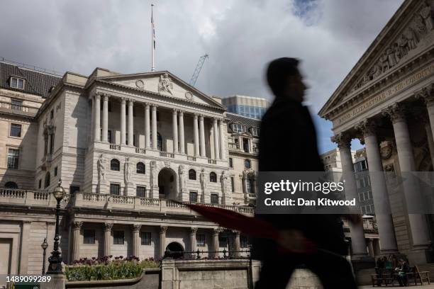 Man holding an umbrella walks past the Bank of England ahead of the central banks interest rate announcement on May 11, 2023 in London, England. The...