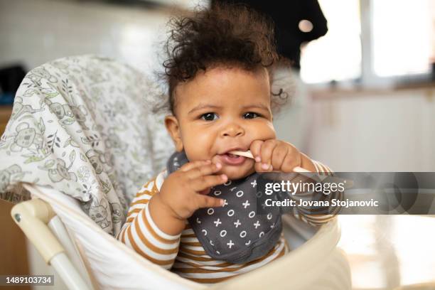baby boy eating blend food on a high chair - high chair stock pictures, royalty-free photos & images